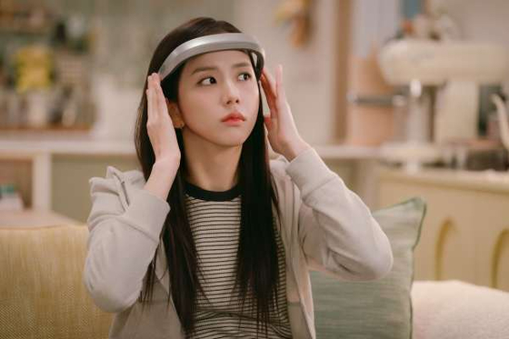Jisoo as Mirae in 'Monthly Boyfriend' with a thoughtful expression, looking off-camera in a brightly lit room.