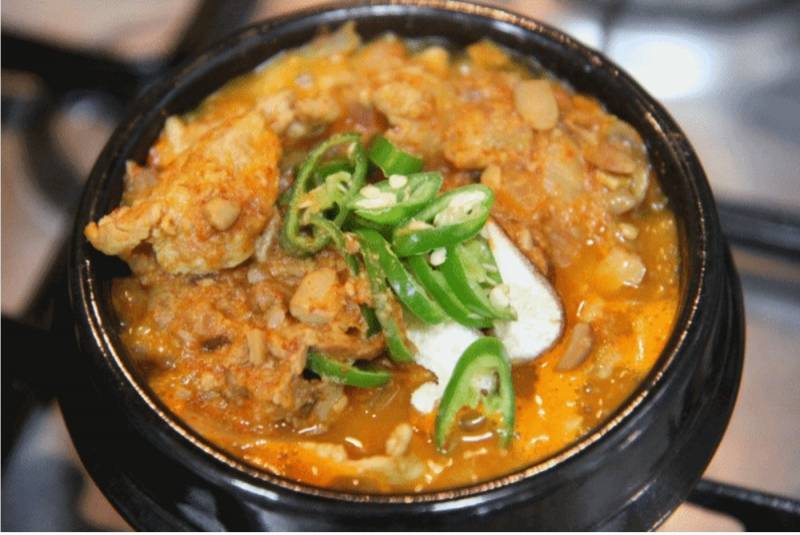 A traditional Korean soup bowl served with various side dishes, representing the classic heavy meal style Gen Z is currently avoiding.
