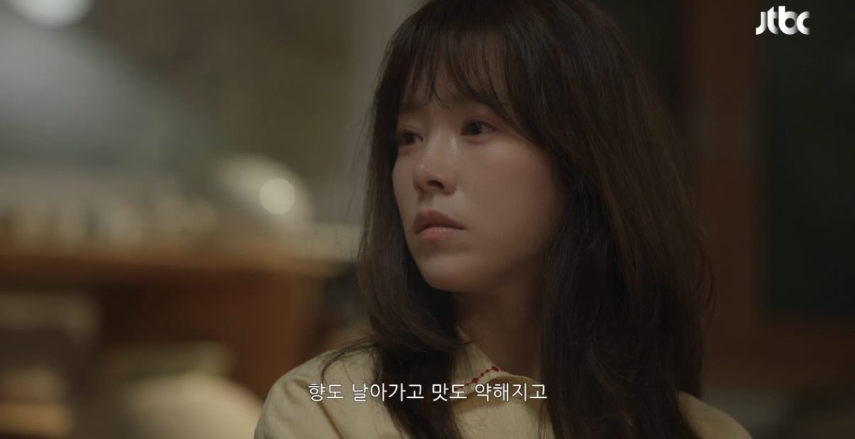 Two characters, a man and a woman, stand close together in a dimly lit, modern interior, looking at each other with intense expressions, suggesting a moment of high emotional tension or a critical conversation.