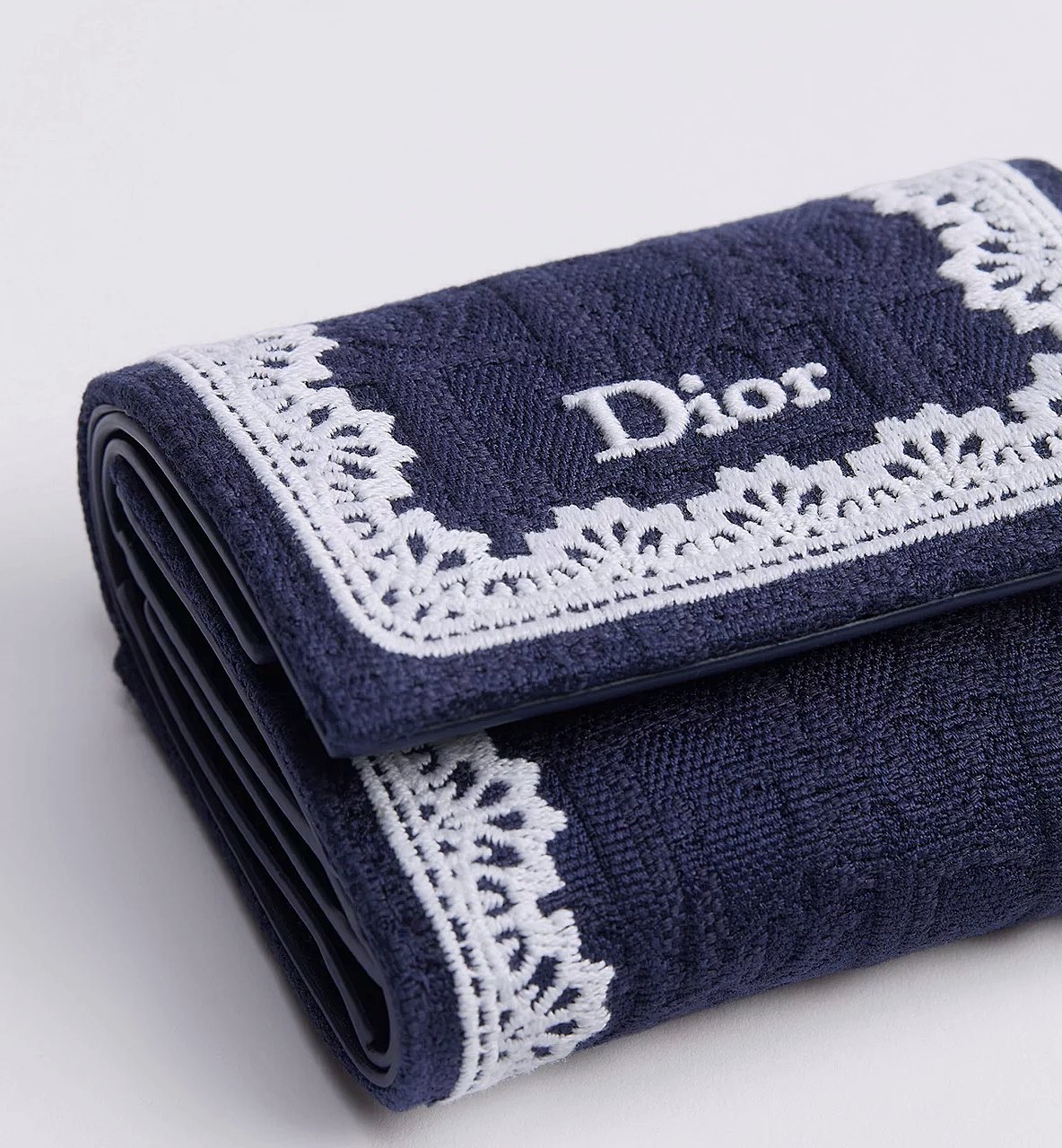 The Dior Japan exclusive mini wallet in a vibrant pastel blue, showcasing its compact size and elegant design against a soft background.