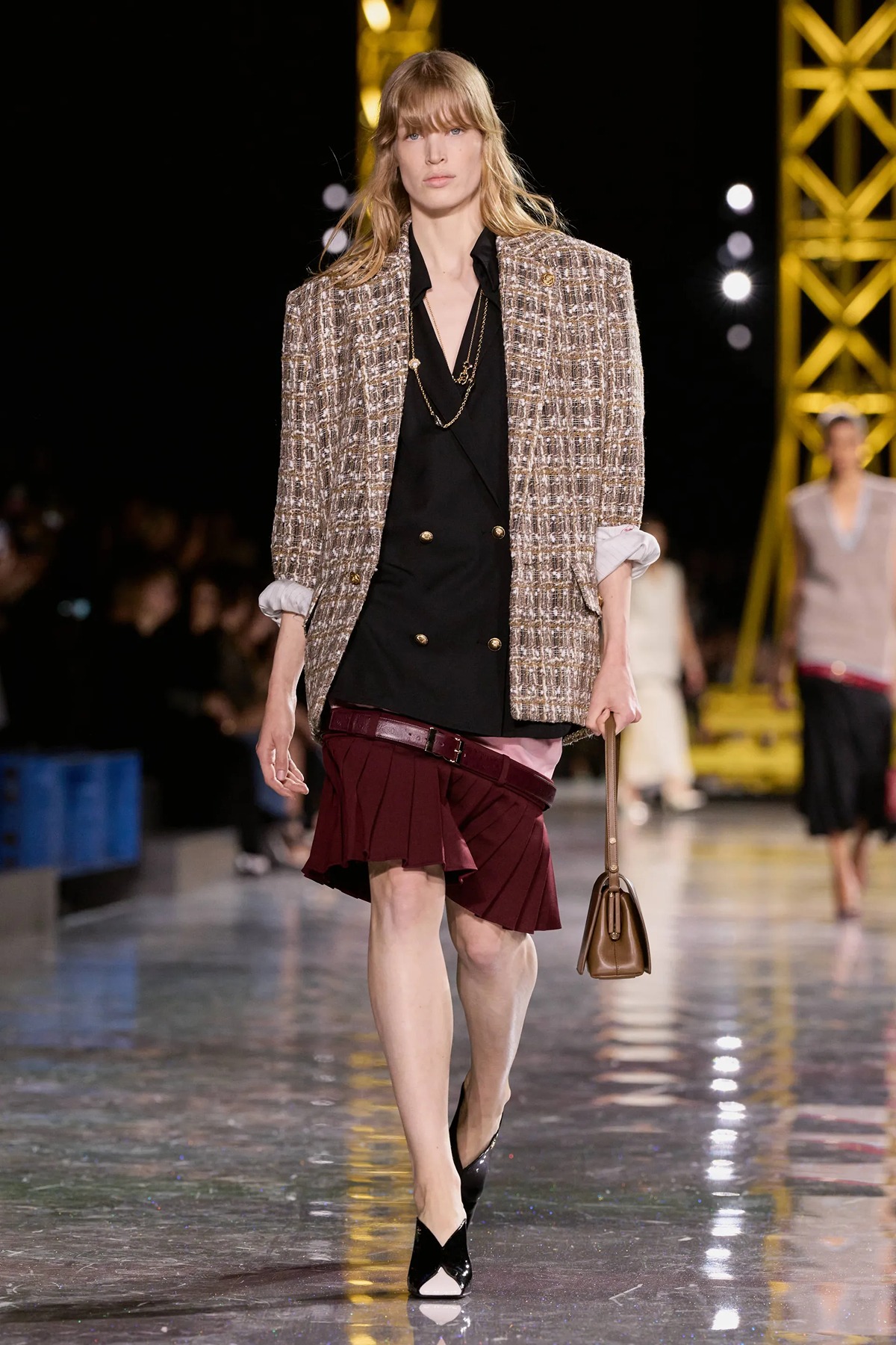 A model walking the Chanel runway in an ultra-low waist skirt and matching top, showing a significant amount of the midriff and hip area.