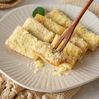 A close-up of Chang-eok Pumpkin Injeolmi showing the soft yellow castella crumbs and chewy rice cake texture.