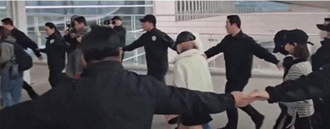 Security guards forming a circular human chain around Hearts2Hearts members at Incheon Airport