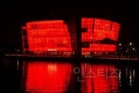 A secondary AI-generated visual showing the red lighting effect on Seoul's urban architecture