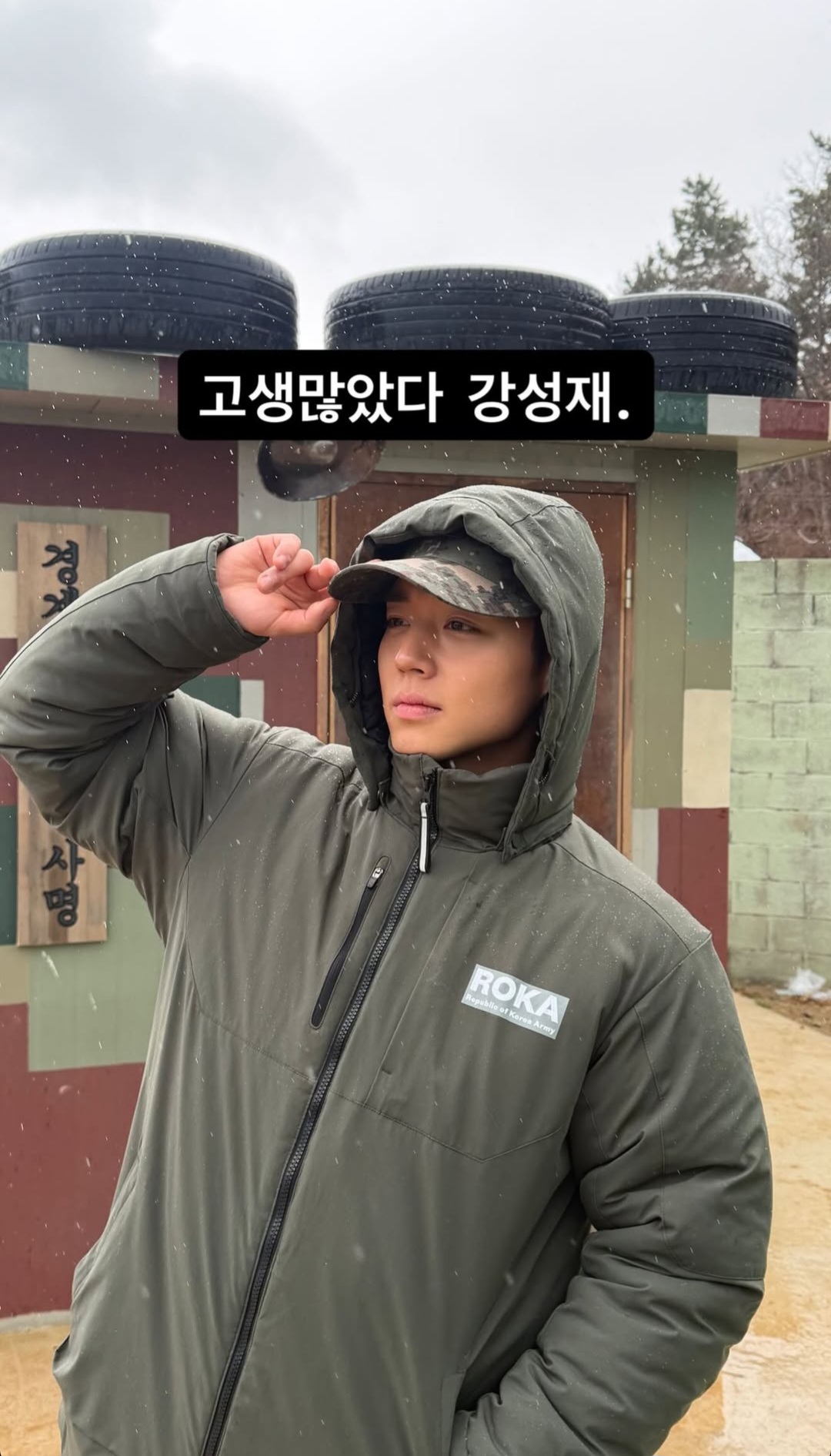 Park Jihoon smiling on set, wearing a military uniform and a chef's hat, holding a clapboard