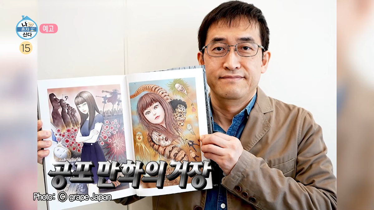 Junji Ito focused intently on his drawing, holding a pen and looking at his work with concentration.