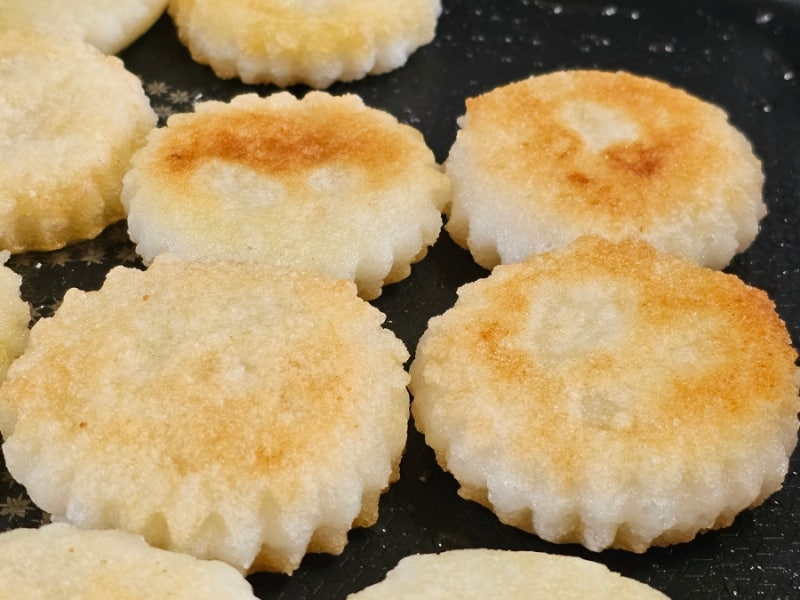 A stack of Jireum-tteok on a traditional wooden tray, highlighting the star-shaped edges and golden color.