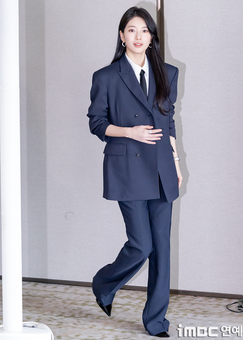 Suzy posing in a way that highlights her elegant and professional office-style wardrobe
