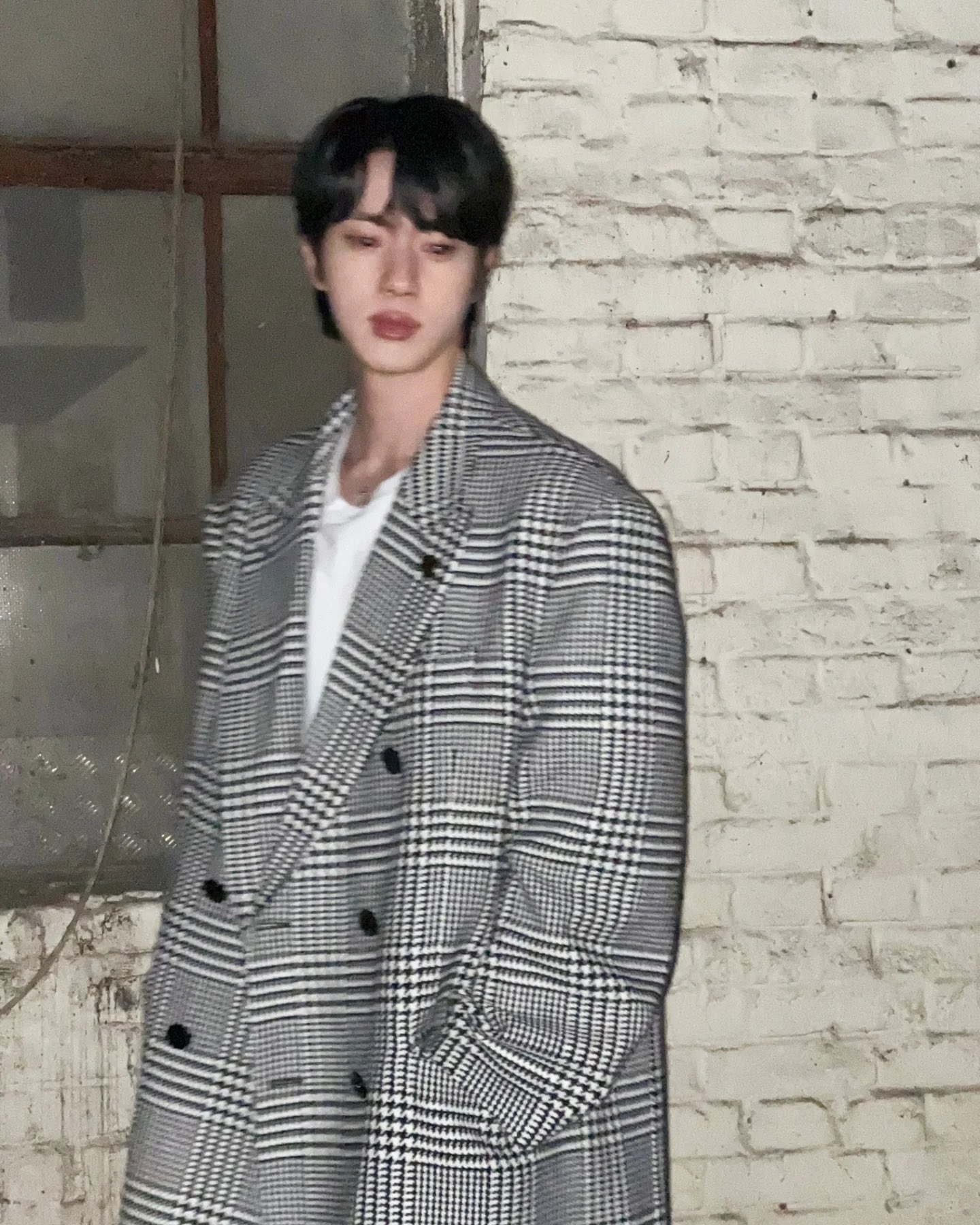 BTSジンが控えめな表情でカメラを見つめるポートレート