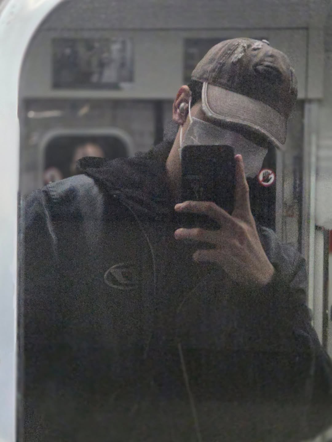 TXT's Soobin wearing a baseball cap and face mask, looking casual on the subway.