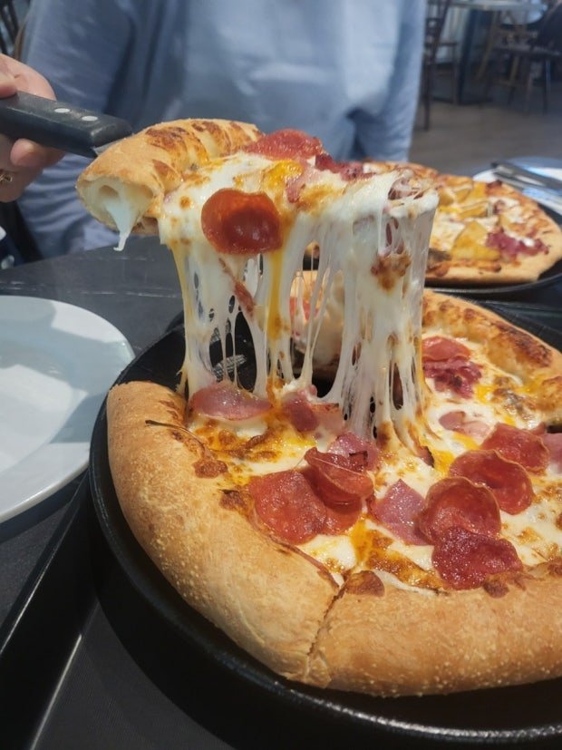 The exterior of the Lee Jae-mo Pizza restaurant in Busan with people waiting in line