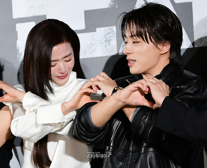 Jun Ji-hyun covering her mouth while laughing, with Koo Kyo-hwan looking on with a mischievous grin.